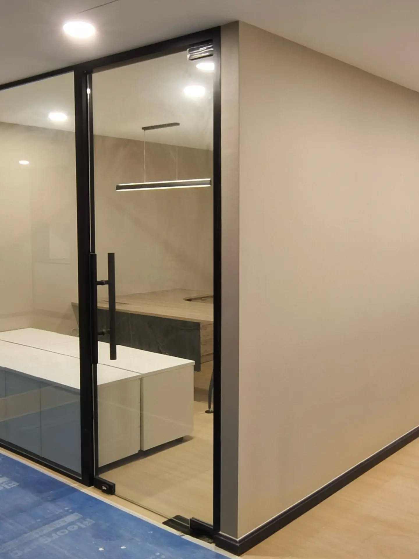 A private office enclosed in black-framed glass, with a desk inside.
