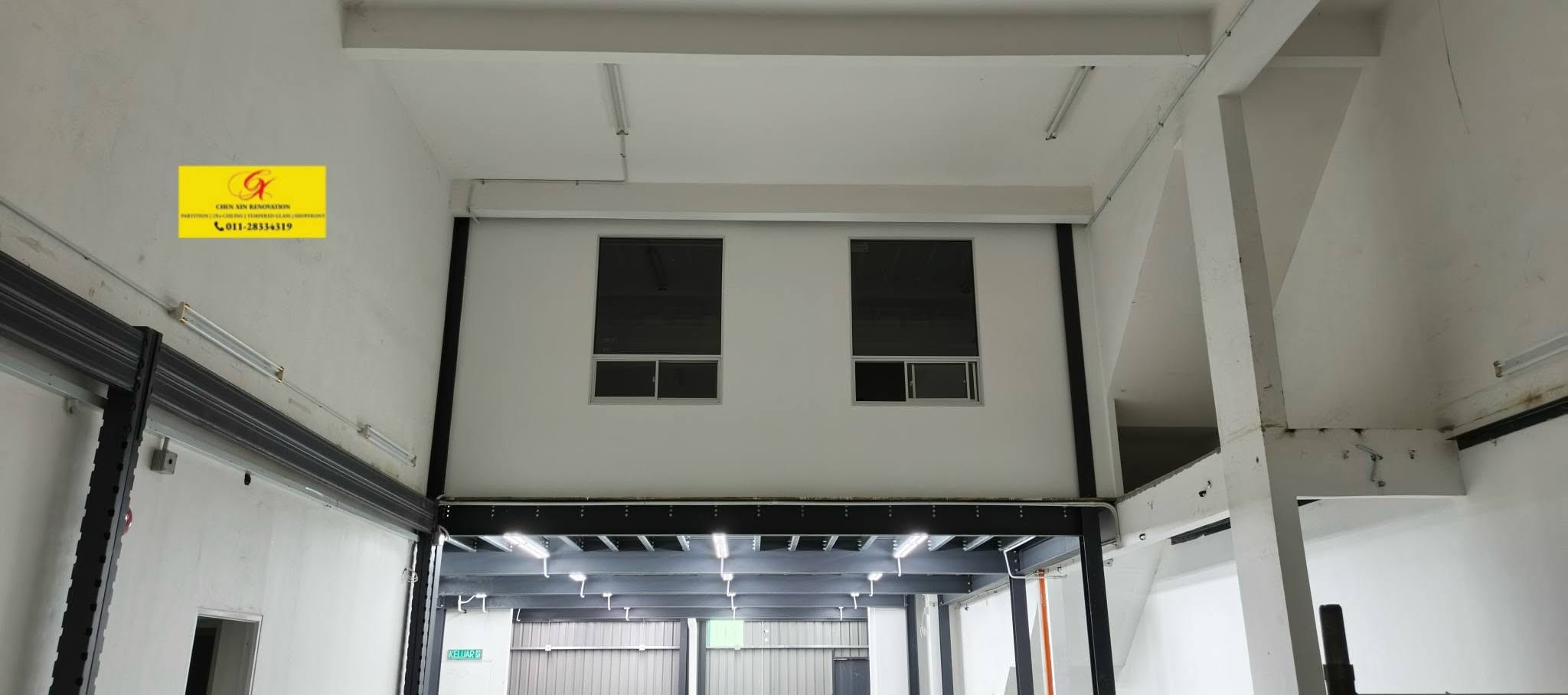 A factory interior with a mezzanine office built above the floor, its windows looking down onto the works.