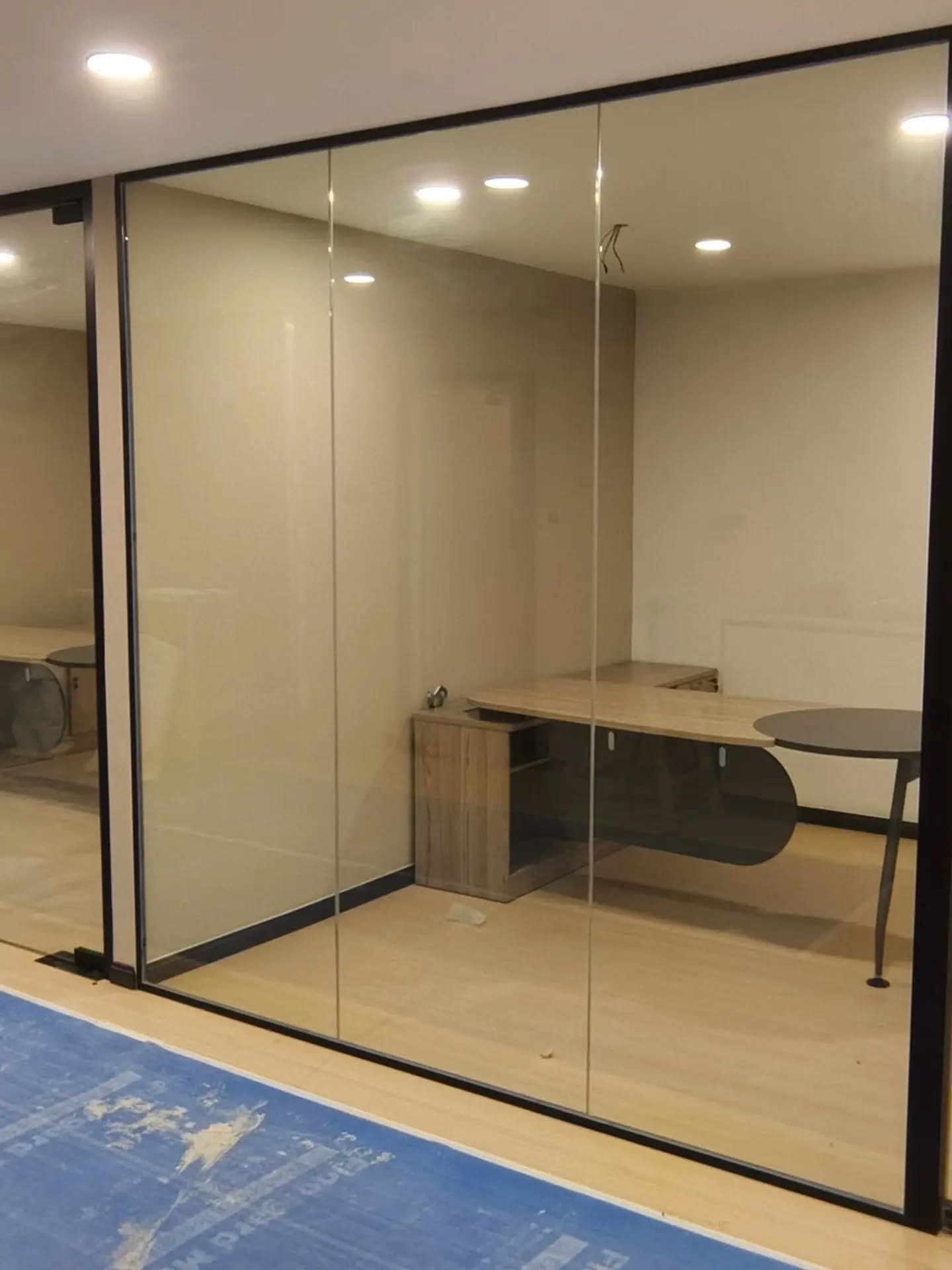 A glass partition with a frosted privacy band, under a dark ceiling bulkhead above timber cabinetry.